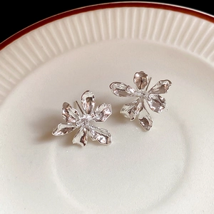 Detailed macro view of 3D silver flower earrings with natural textured metal finish