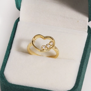 Détail d'une bague coeur en or 14 carats avec trois zircons dans un écrin en velours