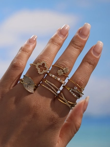 Close-up of golden ring set with sparkling zircons and pearls on hand under blue sky
