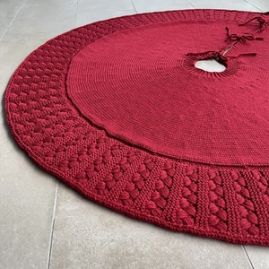 Detailed knit texture of a red circular Christmas tree skirt with woven patterns