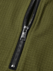 Close-up of the silver metal zipper and olive green waffle knit fabric on the polo shirt