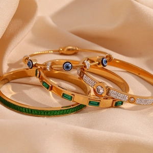 Detail of 18K gold plated stainless steel bracelets with green zircons and evil eye charms