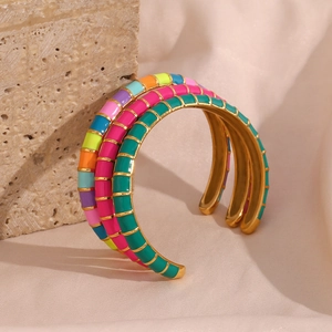 Macro shot of 18K gold plated multi-color enamel cuff bracelet on decorative stones
