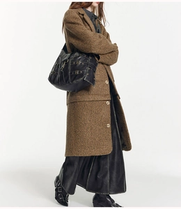 Model showcasing a black leather tote bag with metallic buckles and belt details