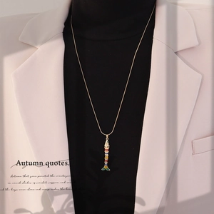 Detailed shot of an articulated koi fish necklace in gold finish on a model
