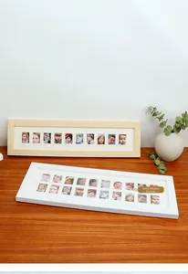 Close-up of minimalist wooden multi-aperture photo frame with white grid mat for baby photos