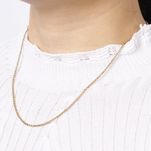 Close-up of a slim golden stainless steel pearl chain necklace worn by a model