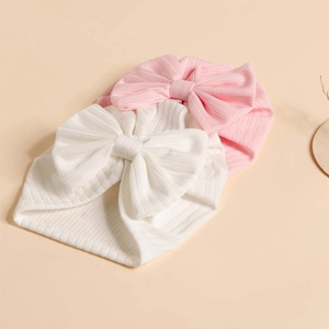 Detailed view of soft ribbed baby turban headbands with large bows in pink and white