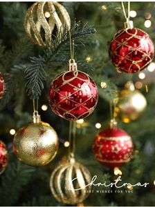 Detail of red and gold Christmas balls hanging on a decorated tree with festive lighting