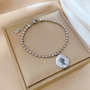 Detail of silver beaded chain bracelet featuring an Elizabeth II coin pendant on a box