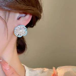 Detailed view of hollow flower earrings with blue petals and center pearl on model
