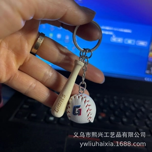 Macro detail of a 2CM baseball keychain featuring a mini wooden bat and leather stitched ball