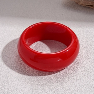 Close-up of wide irregular round resin bangle in vibrant dark red with a glossy finish
