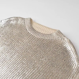 Detailed view of silver sequin knit fabric and crew neck collar texture on the sweater