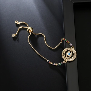 Detail of adjustable gold bracelet with colorful zircon Evil Eye and sliding clasp charm