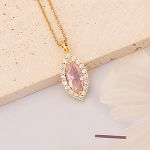 Macro detail of gold necklace with pink oval gemstone pendant and white diamond halo