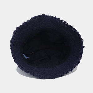 Detailed close-up of dark blue bucket hat with frayed edges and inner brand wash label