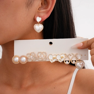 Detail view of gold earrings set with pearls, enamel flower and sparkling rhinestones