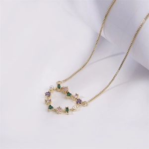 Gold plated heart pendant necklace with colorful zircons and pearls on white background