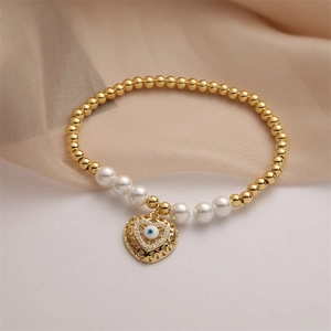 Detail of beaded bracelet with pearls, gold beads, and a heart evil eye charm