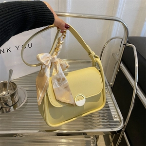 Light yellow leather underarm bag with metal buckle and cherry print scarf detail