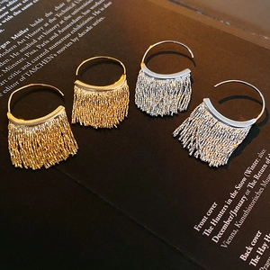 Detailed view of C-shaped gold and silver tassel earrings on a vintage book