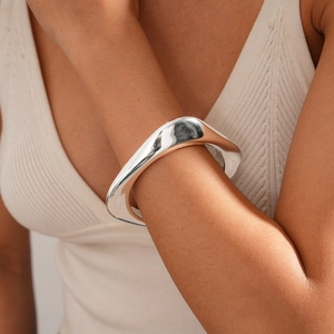 Macro shot of oversized irregular silver wave bangle with a polished mirror finish