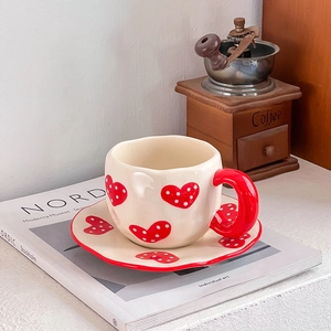 Detail of hand-pinched ceramic coffee set with red heart pattern and polka dots on a tray