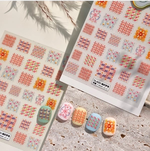 Detail of 3D embossed nail stickers with knit textures and floral patterns on ivory stone