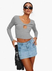 Détail d'une mini-jupe en jean bleu assortie à un haut gris en maille avec détail découpé
