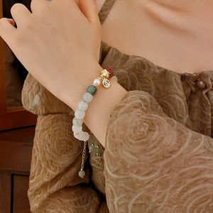 Close-up of beaded bracelet with Fu character pendant and adjustable gold chain