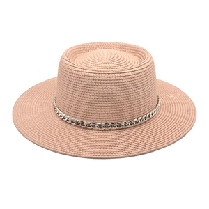 Detail of light pink boater hat with fine straw weave and silver metal chain trim