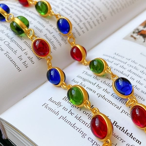 Detail of vintage gold necklace with colorful oval gemstones on open book pages