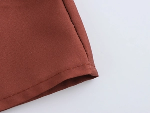 Détail macro de l'ourlet en tissu floral rouge-brun avec couture précise et texture