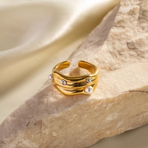Close-up of gold-plated wavy ring with pearls and zircons on a natural stone base