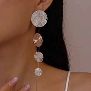 Détail de boucles d'oreilles argentées à disques spirales portées par un mannequin