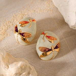 Detailed macro shot of vintage gold dragonfly earrings with colorful enamel inlay on stone