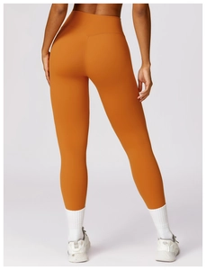 Detail view of high-waist yoga leggings in deep orange with back V-shaped stitching