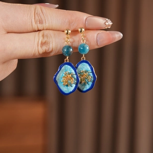 Macro shot of vintage gold-plated blue floral earrings with detailed resin texture