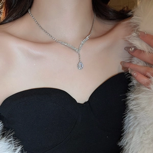 Close-up of a silver water drop pendant necklace with diamonds worn by a model