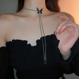 Detail of silver chain necklace featuring a black enamel butterfly pendant on model
