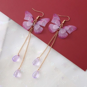 Détail de boucles d'oreilles papillon avec chaînes dorées et pendentifs en goutte