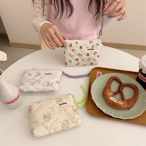Quilted floral coin purse with cute bear patterns displayed on a white cafe table