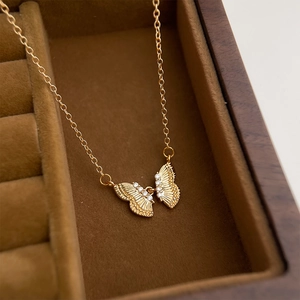 Macro detail of 18K gold butterfly necklace with zircon accents in a premium jewelry box