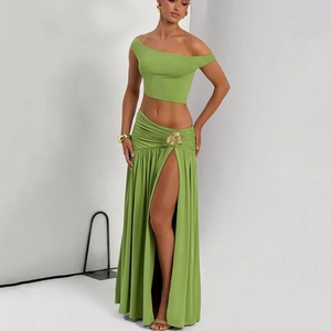 Detail view of the grass green skirt featuring a high side slit and gold flower accent