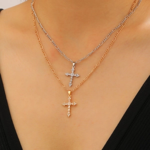 Macro shot of layered gold and silver cross pendants with cubic zirconia on box chains
