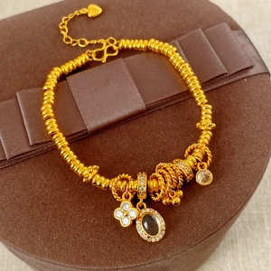 Detail of 24k gold clover bracelet with black zircon charms on a luxury gift box