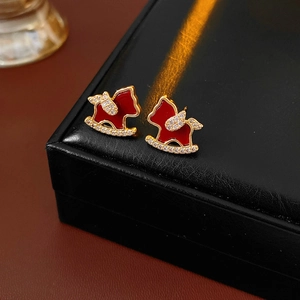 Close-up of golden rocking horse stud earrings with red enamel and sparkling crystals