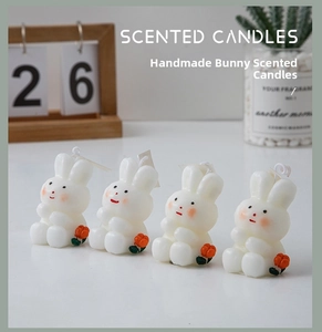 Macro detail of four rabbit-shaped scented candles with delicate orange flower accents
