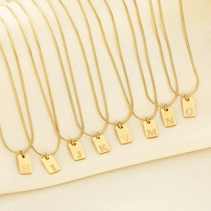 Gold letter pendant necklaces on box chains featuring engraved initials H to O